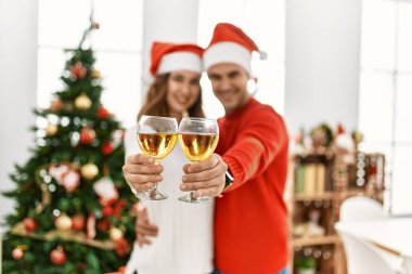 Genç İspanyol çift Noel şapkası takıp evde şampanyayla kadeh kaldırıyor..