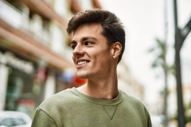 Genç İspanyol adam gülümseyerek şehirde mutlu mesut dikiliyor..