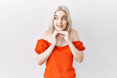 Kafkasyalı genç bir kadın izole edilmiş arka planda duruyor. Gergin ve heyecanlı bir şekilde çene kenarına bakıyor. 