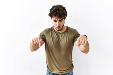 İzole edilmiş beyaz arka planda dikilen İspanyol bir adam parmaklarını göstererek reklamını yapıyor, şaşırmış bir yüz ve açık bir ağız. 