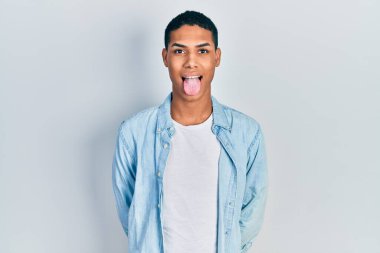 Genç, Afro-Amerikalı, günlük kıyafetler giymiş, dilini komik bir ifadeyle dışarı çıkaran bir adam. duygu kavramı. 