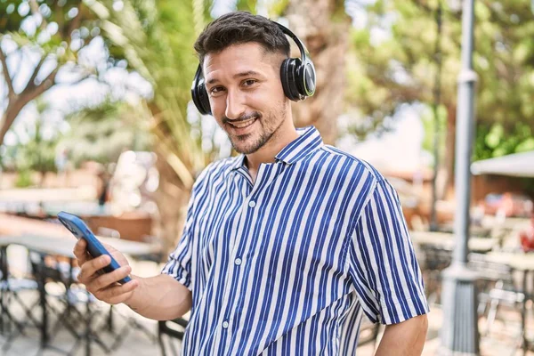 Młody Przystojny Mężczyzna Nosi Słuchawki Pomocą Smartfona Parku — Zdjęcie stockowe