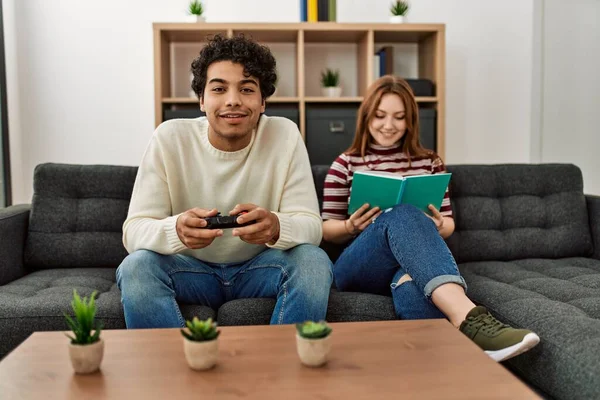 Homem Jogando Videogame Enquanto Namorada Lendo Livro Casa — Fotografia de Stock