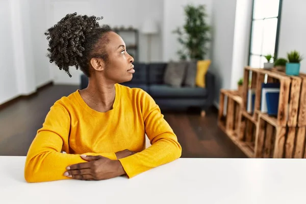 Jovem Afro Americana Vestindo Roupas Casuais Sentada Mesa Casa Olhando — Fotografia de Stock