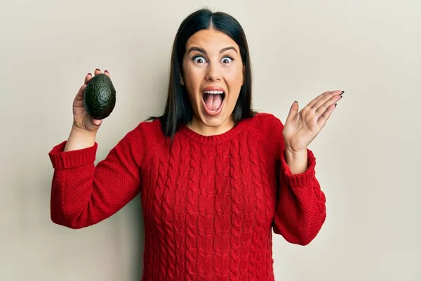 Beautiful Brunette Woman Holding Avocado Celebrating Achievement Happy Smile Winner — Stock Photo, Image