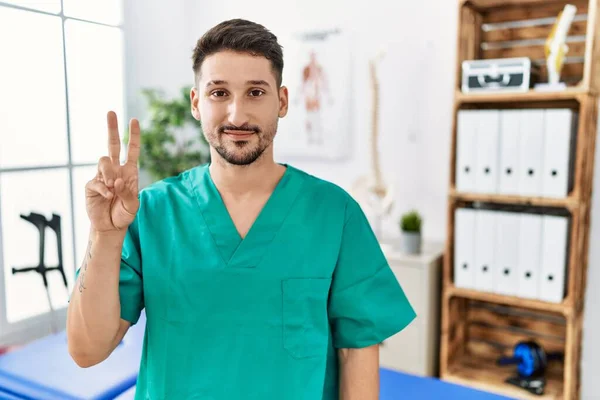 Ağrı Kesici Kliniğinde Çalışan Genç Fizyoterapist Iki Numarayı Gösterip Işaret — Stok fotoğraf