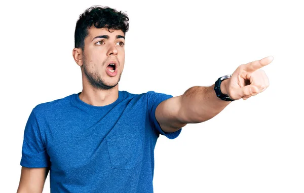 Joven Hombre Hispano Con Camiseta Casual Señalando Con Dedo Sorprendido —  Fotos de Stock