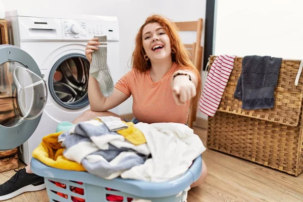 指でカメラを指差す汚い洗濯機に汚れた洗濯機を置く若い赤毛の女性は 陽気で肯定的な笑顔 — ストック写真