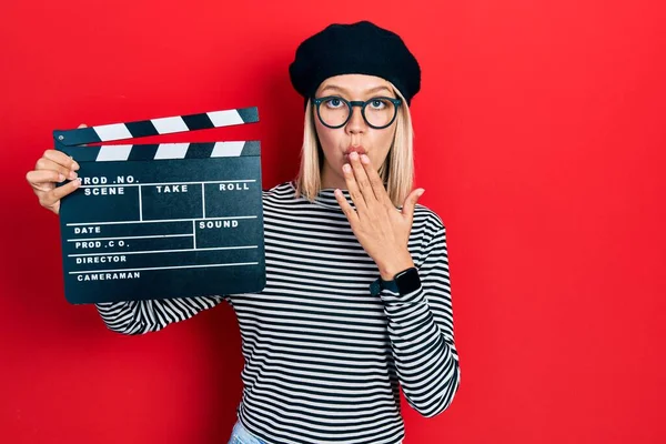 Mooie Blonde Vrouw Met Videofilm Klapbord Mond Met Hand Geschokt — Stockfoto