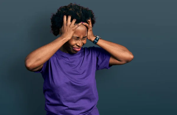 アフロヘアのアフリカ系アメリカ人女性は 痛みや片頭痛のために絶望的な頭痛やストレスに苦しんでカジュアルな紫色のTシャツを着ています 手を頭に — ストック写真