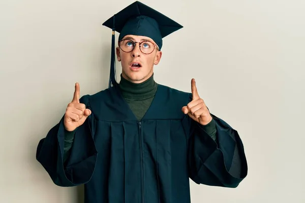 Young Caucasian Man Wearing Graduation Cap Ceremony Robe Amazed Surprised — Stock Photo, Image