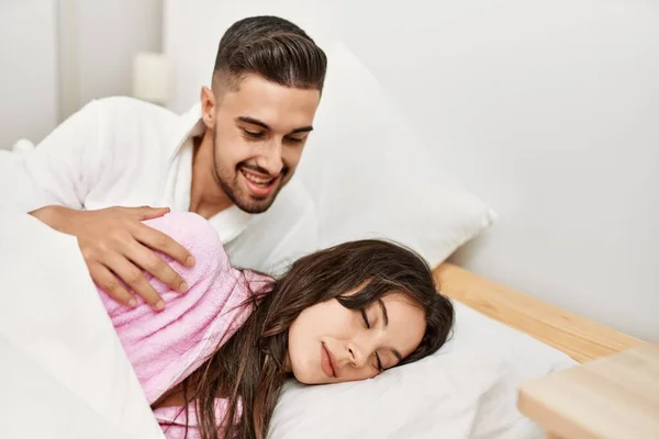 年轻的惊慌失措的男人在床上看着他困倦的女朋友 — 图库照片
