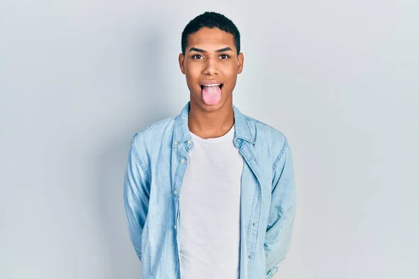 穿着休闲服的年轻的非洲裔美国人 带着滑稽的表情 把舌头伸出来很高兴 情感概念 — 图库照片