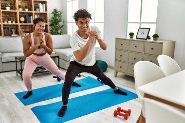 Genç Latin sporcu çift gülümseyerek evde mutlu bir antrenman yapıyor..