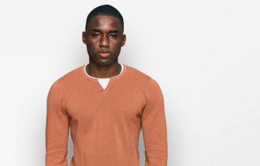 Yüzünde ciddi bir ifade olan günlük kıyafetler giyen genç bir Afro-Amerikan. Basit ve doğal bir şekilde kameraya bakıyorsun.. 