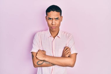 Genç, Afro-Amerikalı, sıradan kıyafetler giyen, kuşkucu ve gergin, yüzünde çapraz kollu tasvip etmeyen bir ifade var. negatif kişi. 