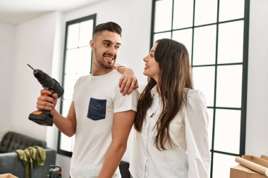 Genç İspanyol çift yeni evinde talim yaparken mutlu gülümsüyor..