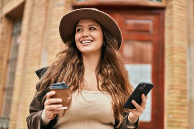 Genç İspanyol turist kadın akıllı telefon kullanıyor ve şehirde kahve içiyor..