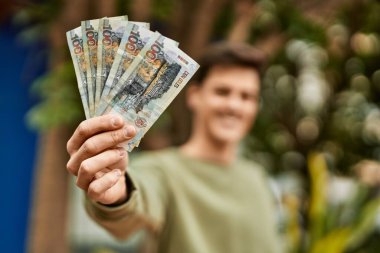 Genç İspanyol gülümseyen adam Peru tabanlı banknotları şehirde tutarken mutlu..