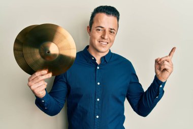 Altın zilli tabakları tutan yakışıklı genç adam mutlu bir şekilde gülümsüyor. 