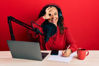 Güzel, orta yaşlı bir kadın radyo stüdyosunda çalışıyor. Gülümsüyor, gülümsüyor. 