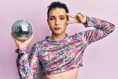 Parlak disko topu tutan yakışıklı bir adam yüzünde ciddi bir ifadeyle rahatlamış. Basit ve doğal bir şekilde kameraya bakıyorsun.. 