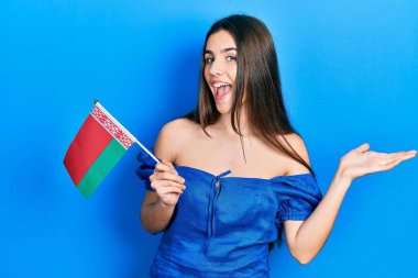 Genç esmer ergen, Belarus bayrağını tutarak zaferi mutlu bir gülümsemeyle ve kazanan ifadeyle kutluyor. 