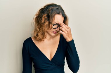 İş gömleği ve gözlük takan genç beyaz kadın yorgun burnu ve gözleri ovuşturup yorgun ve baş ağrısı çekiyor. Stres ve hüsran kavramı. 