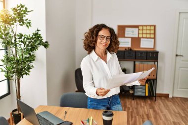 Ofiste çalışırken gülümseyen orta yaşlı İspanyol kadın.