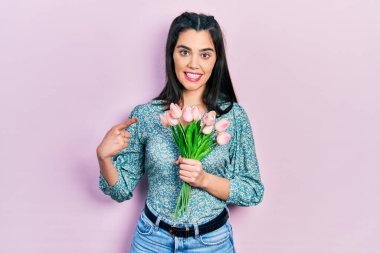 Çiçekleri tutan genç İspanyol kız mutlu bir şekilde elini ve parmağını gösterdi. 