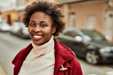 Güzel bir iş adamı Afro saçlı Amerikalı kadın şehirde mutlu ve kendinden emin bir şekilde gülümsüyor.