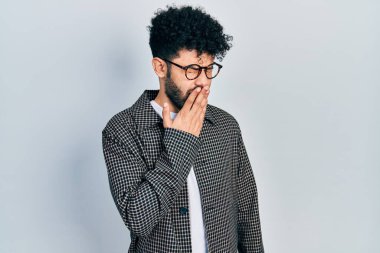 Sakallı, gözlüklü genç bir Arap, ağzını eliyle kapatmaktan sıkılmış. Huzursuz ve uykulu.. 