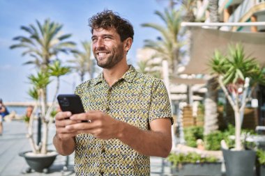 Sokakta akıllı telefon kullanan, kendine güvenen genç bir İspanyol.