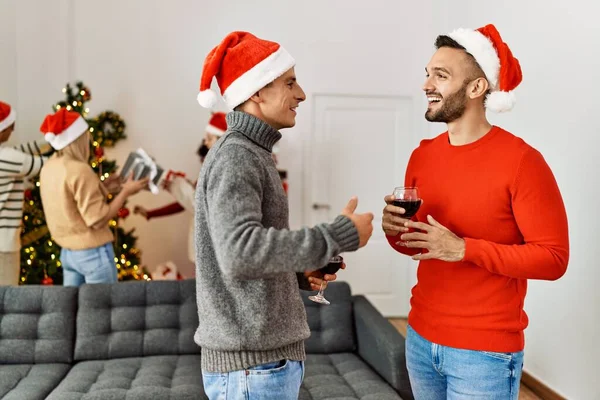 クリスマスを祝う若者のグループ ２人の男がワインを飲みながら家に立って — ストック写真