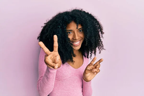 Afro Saçlı Sıradan Pembe Tişörtlü Gülümseyen Parmaklarını Zafer Işareti Yaparken — Stok fotoğraf