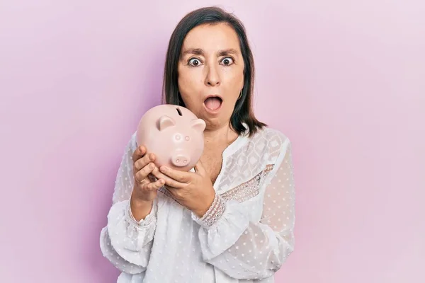 Mulher Hispânica Meia Idade Segurando Banco Porquinho Com Medo Chocado — Fotografia de Stock