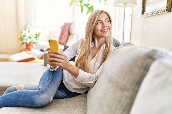 Mujer Rubia Joven Usando Teléfono Inteligente Sentado Sofá Casa — Foto de Stock