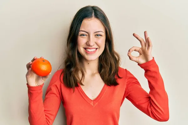 Joven Morena Sosteniendo Naranja Fresca Haciendo Signo Con Los Dedos —  Fotos de Stock