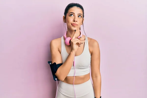Young Hispanic Woman Wearing Gym Clothes Using Headphones Thinking Concentrated — Stock Photo, Image