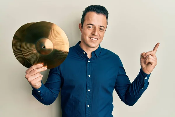 Stilig Ung Man Håller Gyllene Cymbalplattor Ler Glad Pekar Med — Stockfoto