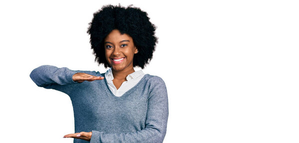 Young african american woman wearing business clothes gesturing with hands showing big and large size sign, measure symbol. smiling looking at the camera. measuring concept. 