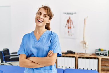 Klinikte kollarını kavuşturmuş genç beyaz fizyoterapist kız..