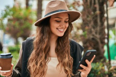 Genç İspanyol turist kadın akıllı telefon kullanıyor ve şehirde kahve içiyor..