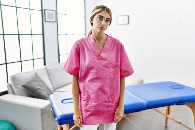 Evde fizyoterapist olarak çalışan genç sarışın kadın yüzünde ciddi bir ifadeyle rahatlamış. Basit ve doğal bir şekilde kameraya bakıyorsun.. 