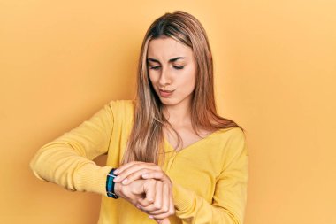 Güzel İspanyol kadın gündelik sarı süveter giyer saati kontrol eder, rahat ve kendinden emin. 