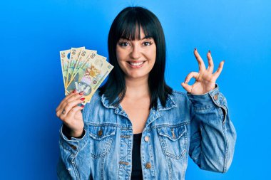 50 Romen Ley banknotunu elinde tutan genç İspanyol kadın parmaklarıyla imza atıyor, gülümseyerek mükemmel bir sembol oluşturuyor. 