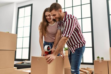 Genç İspanyol çift mutlu bir şekilde gülümsüyor. Yeni evlerinde karton kutu paketliyorlar..