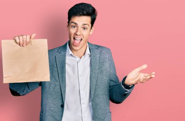 Genç İspanyol iş adamı, elinde kağıt torbayla ekmeği tutarak başarıyı kutluyor. Gülümsüyor ve kazanan el kaldırıyor. 