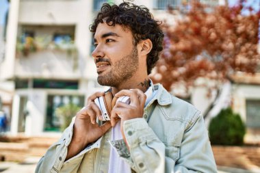 Yakışıklı, sakallı, neşeli, güneşli bir günde kulaklık takan bir İspanyol.