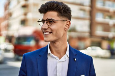 Sokakta kendine güvenen takım elbiseli ve gözlüklü bir genç.